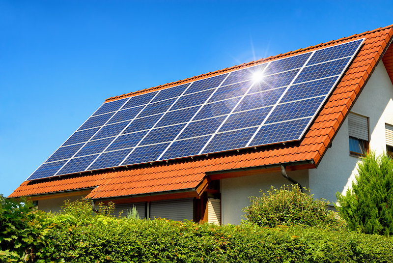 a red roof with a grid of solar panels on a sunny day with a blue sky
